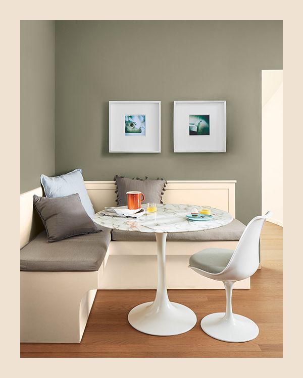A taupe dining room with a built-in white bench and circular marble table and chair.