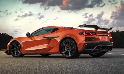 Three-quarter rear view of a 2025 Z06 Coupe in Sebring Orange Tintcoat parked in the middle of an open stretch of road.