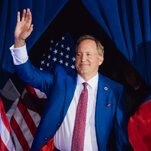 Mr. Paxton waves to the crowd in front of U.S. and Texas flags.