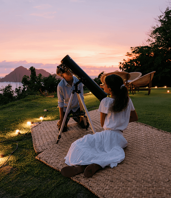 A couple looking through a telescope at dusk.