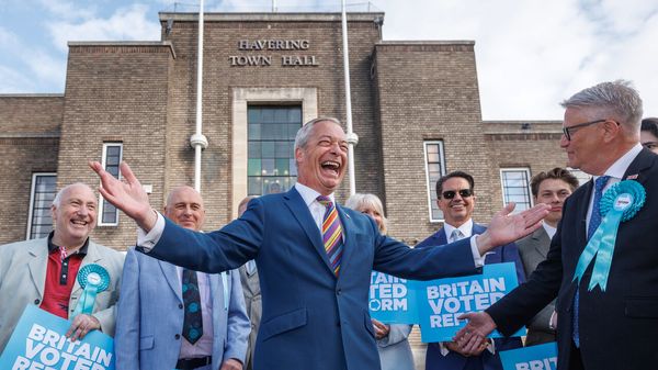 Reform UK leader Nigel Farage poses with winning councillors outside Havering Town Hall following the 2026 local election results in Romford, England.