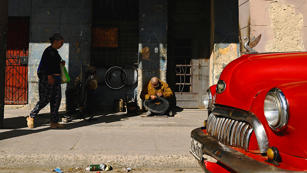 A man repairs a bicycle tire on the sidewalk