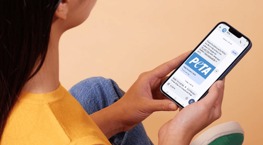 woman holding phone texting PETAs mobile list