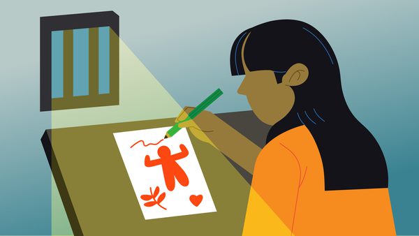 woman wearing orange writes and draws on paper as light comes in through bars