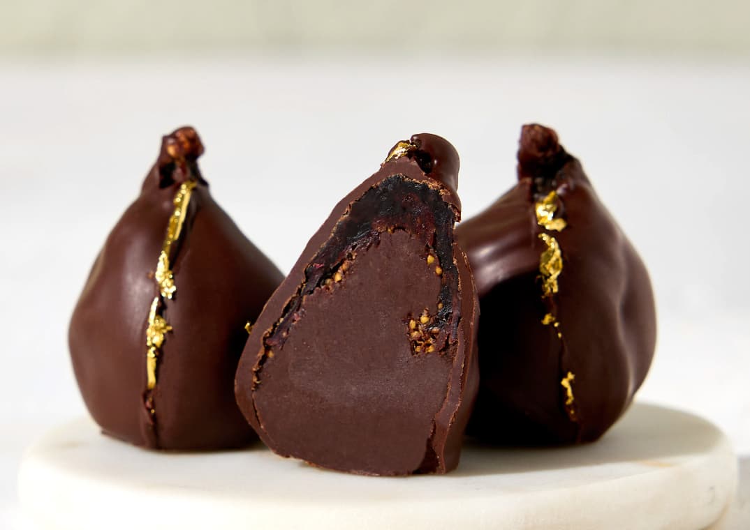 Three Chocolate-Dipped Fig Truffles. One is sliced open.