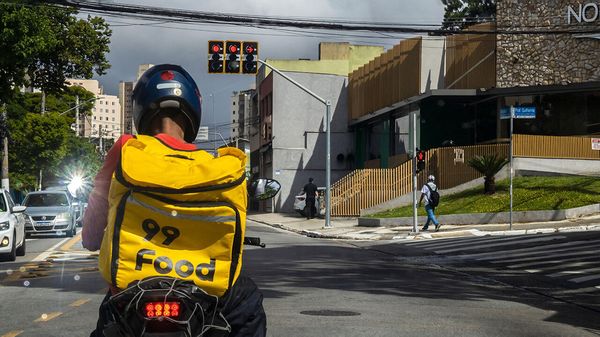 A food delivery courier of the 99 Food on a motorcycle waits at a traffic light in Sao Paulo.