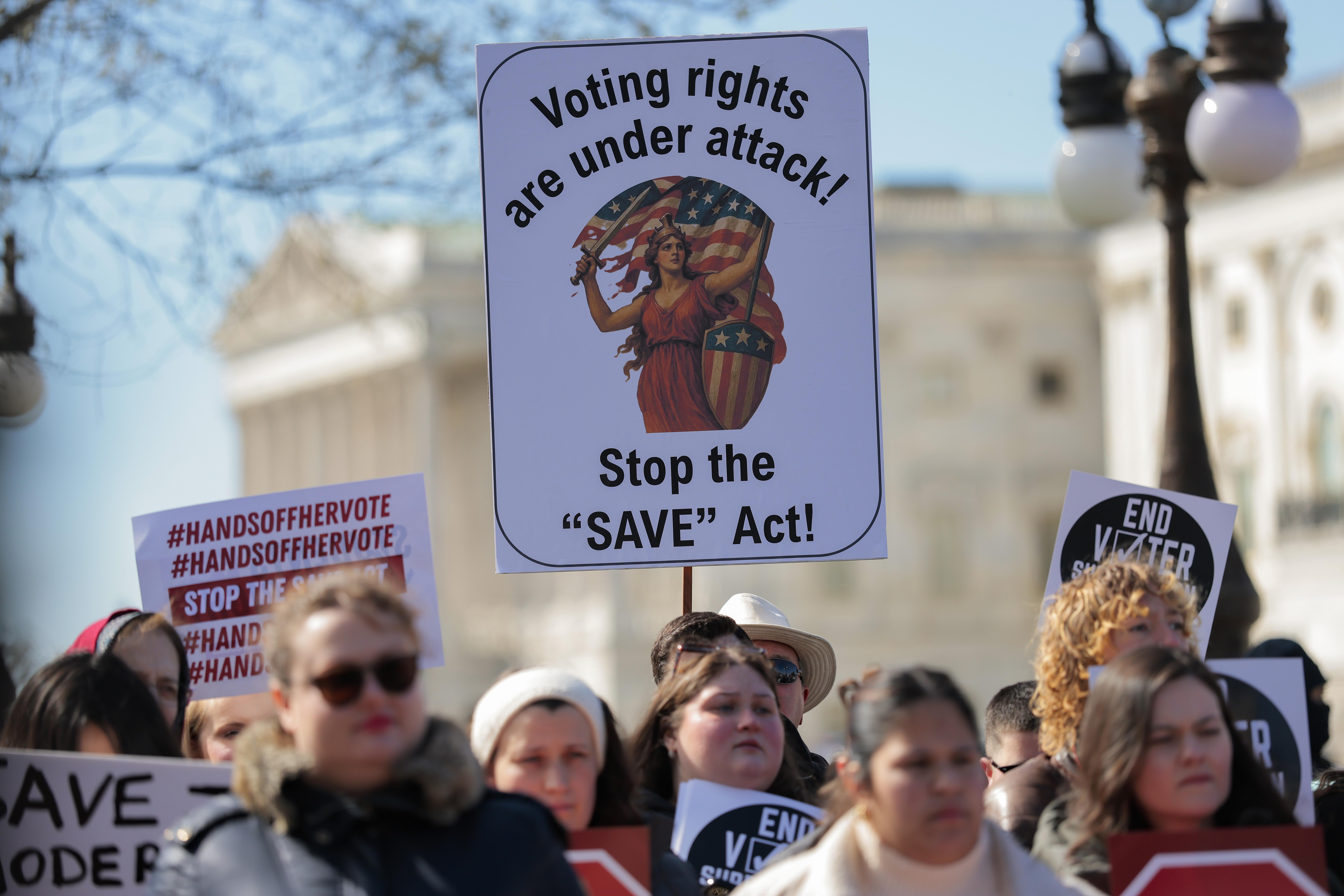 Protesters holding signs against the SAVE Act.