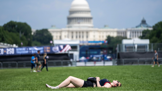 A woman lying on the grass before a large building.
