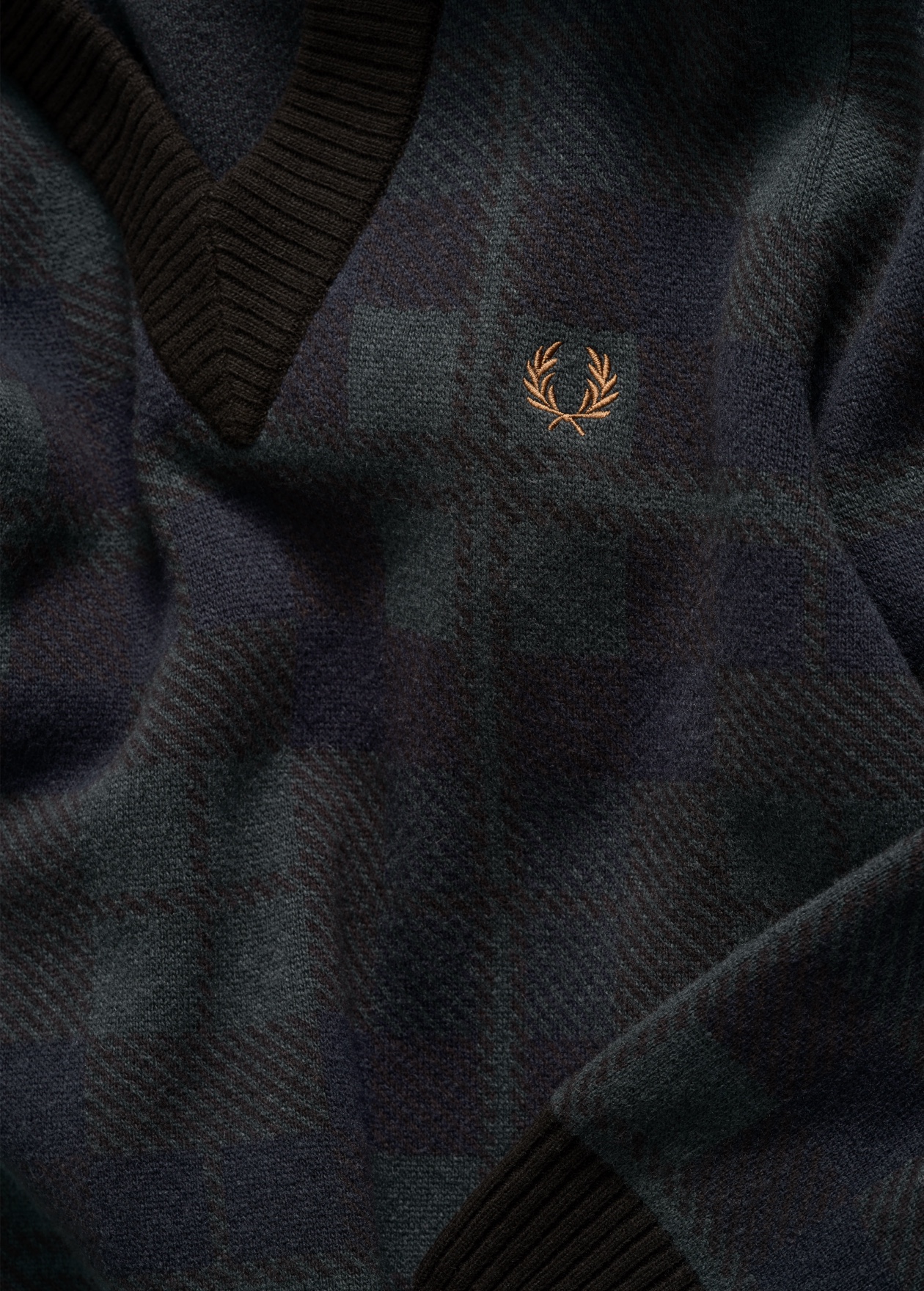 The Black Watch Tartan edit: photo is a detailed close-up of the black tartan pattern on a knitted v-neck jumper