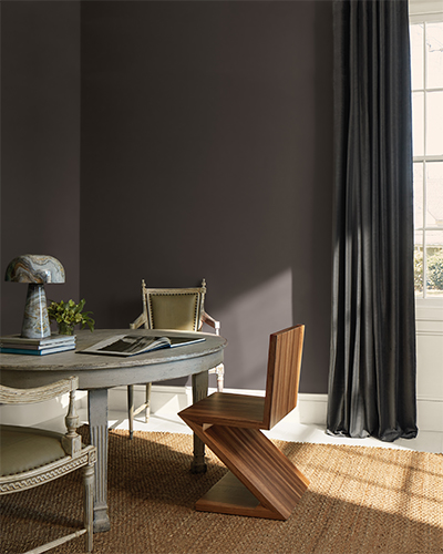 A brown dining room with a circular wood table and three mismatched chairs.