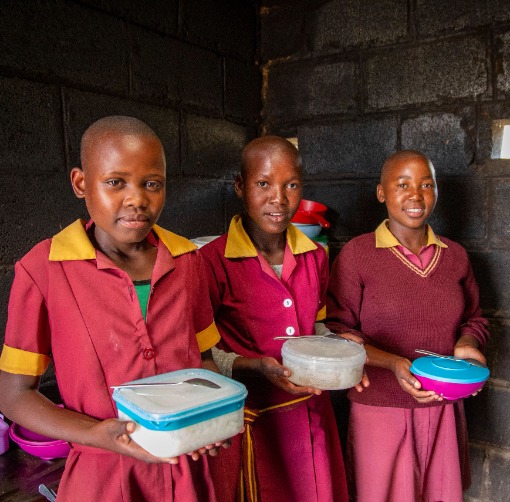 Three girls holding containers with food