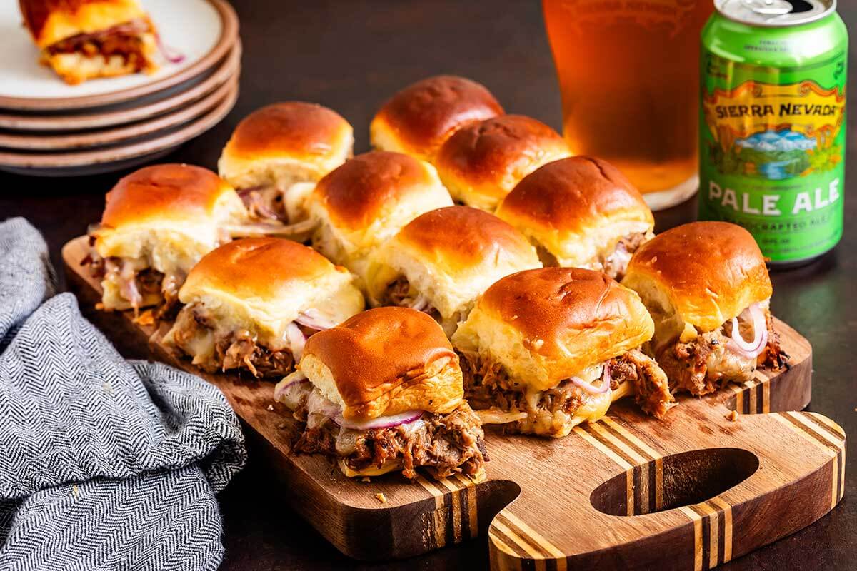 A can of Pale Ale next to pork sliders on a cutting board