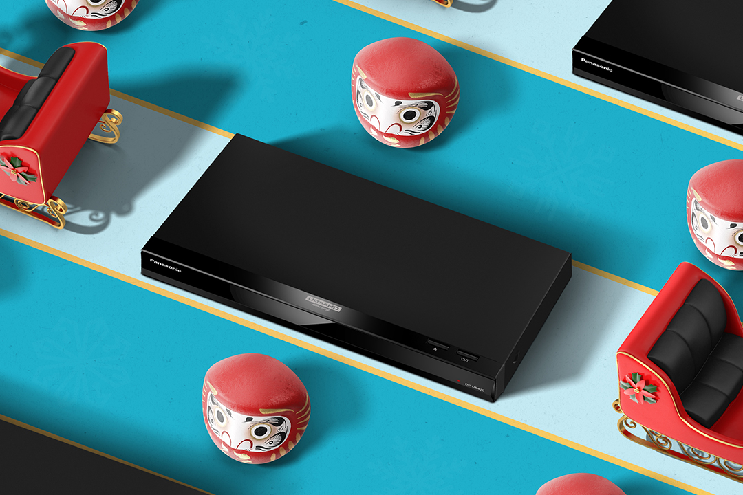 Panasonic BluRay Player arranged with daruma and sleds on blue background