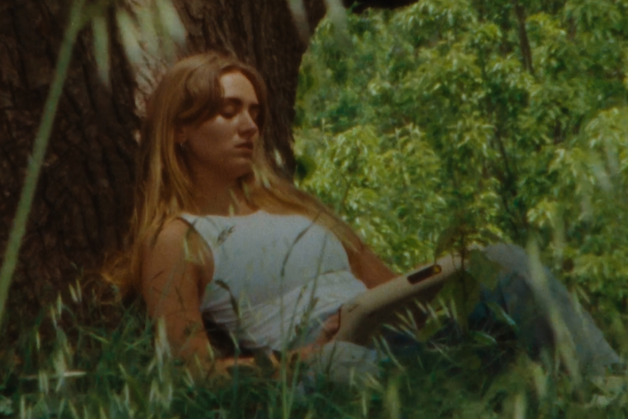 A woman plays an Orchid amongst some lush plants.