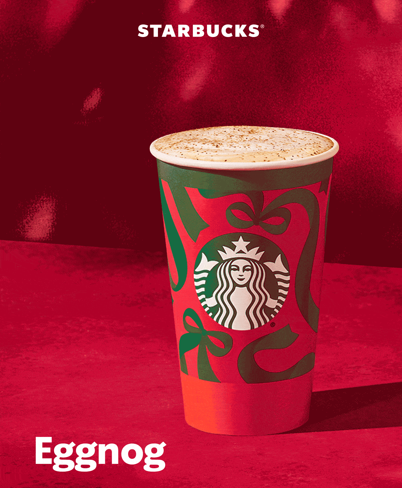 STARBUCKS® | Eggnog is back | Animated image of a hot coffee drink in a Starbucks holiday to-go cup in front of a velvet backdrop. The words "Eggnog is back" flash on the screen sporadically.