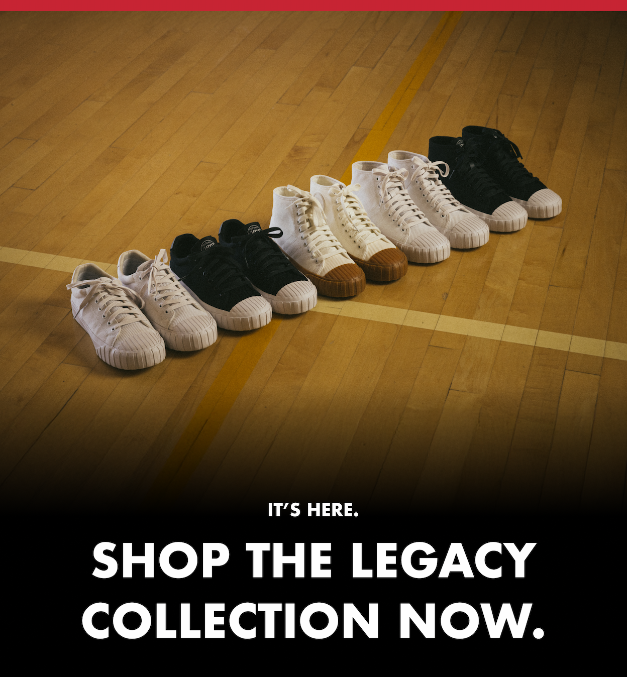 A row of sneakers is neatly lined up on a wooden gym floor, alternating between black and white styles with rubber toe caps. Text below reads: “It’s here. Shop the Legacy Collection now.”