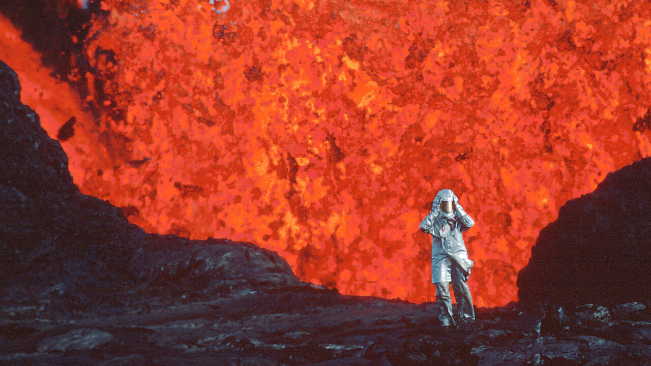 Katia Krafft wearing aluminized suit standing near lava burst at Krafla Volcano, Iceland.