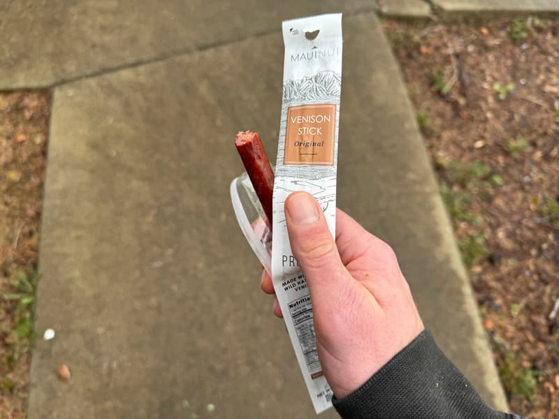 Half eaten Maui Nui venison stick in someone's hand walking down the sidewalk