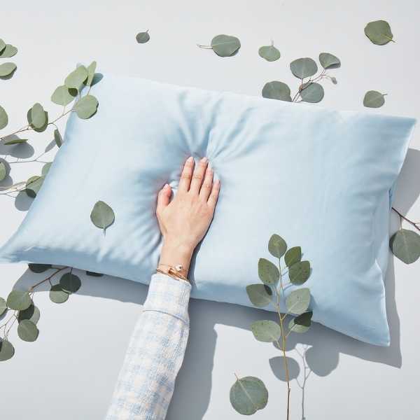 a hand on a pillow surrounded by leaves