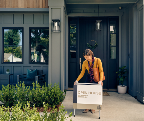 Woman adding open house sign outside home