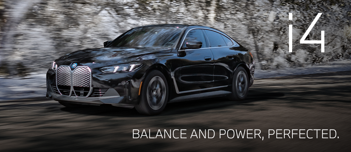 2025 BMW i4 driving down a winter road with snowy trees in the background