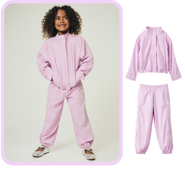 Child wearing pink zip-up jacket and matching pink jogger pants with white sneakers