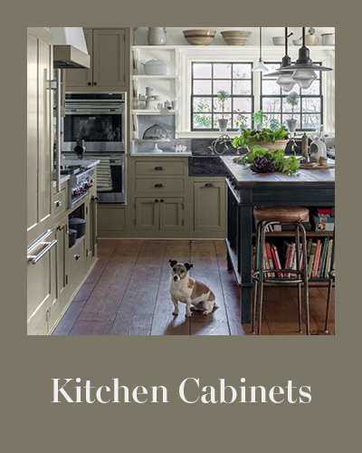 A kitchen with sage green painted cabinets and a white wall with shelves.