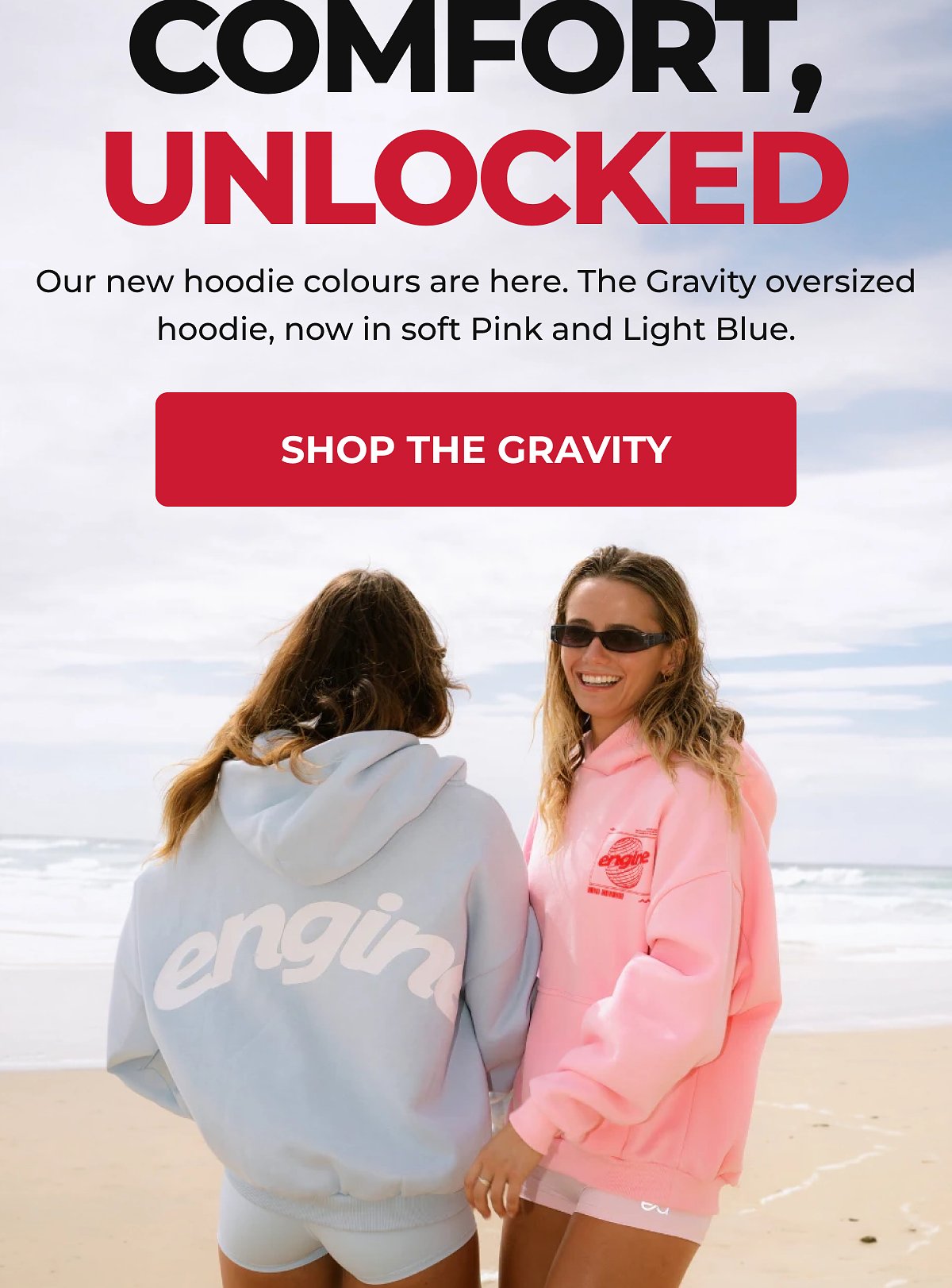 Two women wearing oversized hoodies in soft pink and light blue by the beach.