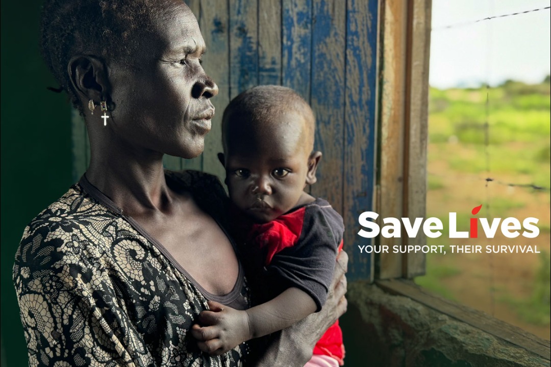 A woman is holding a baby in an outdoor setting.