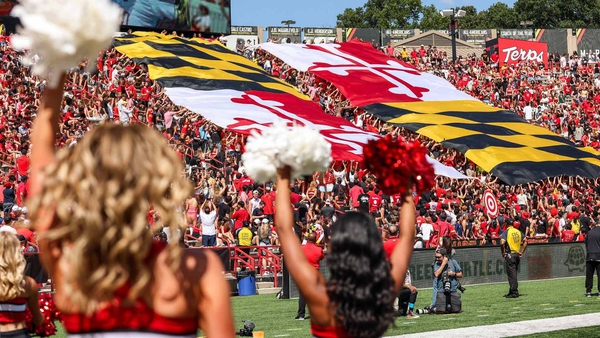 Cheerleaders at a football game with Maryland flags in the stands