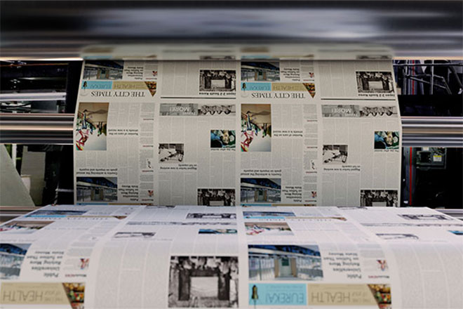 Newspapers rolling off of a printer.