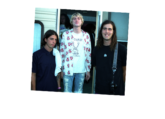 Three band members pose in front of a trailor.