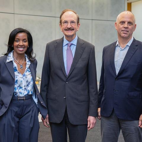 Three people post, smiling toward the viewer in an academic setting.