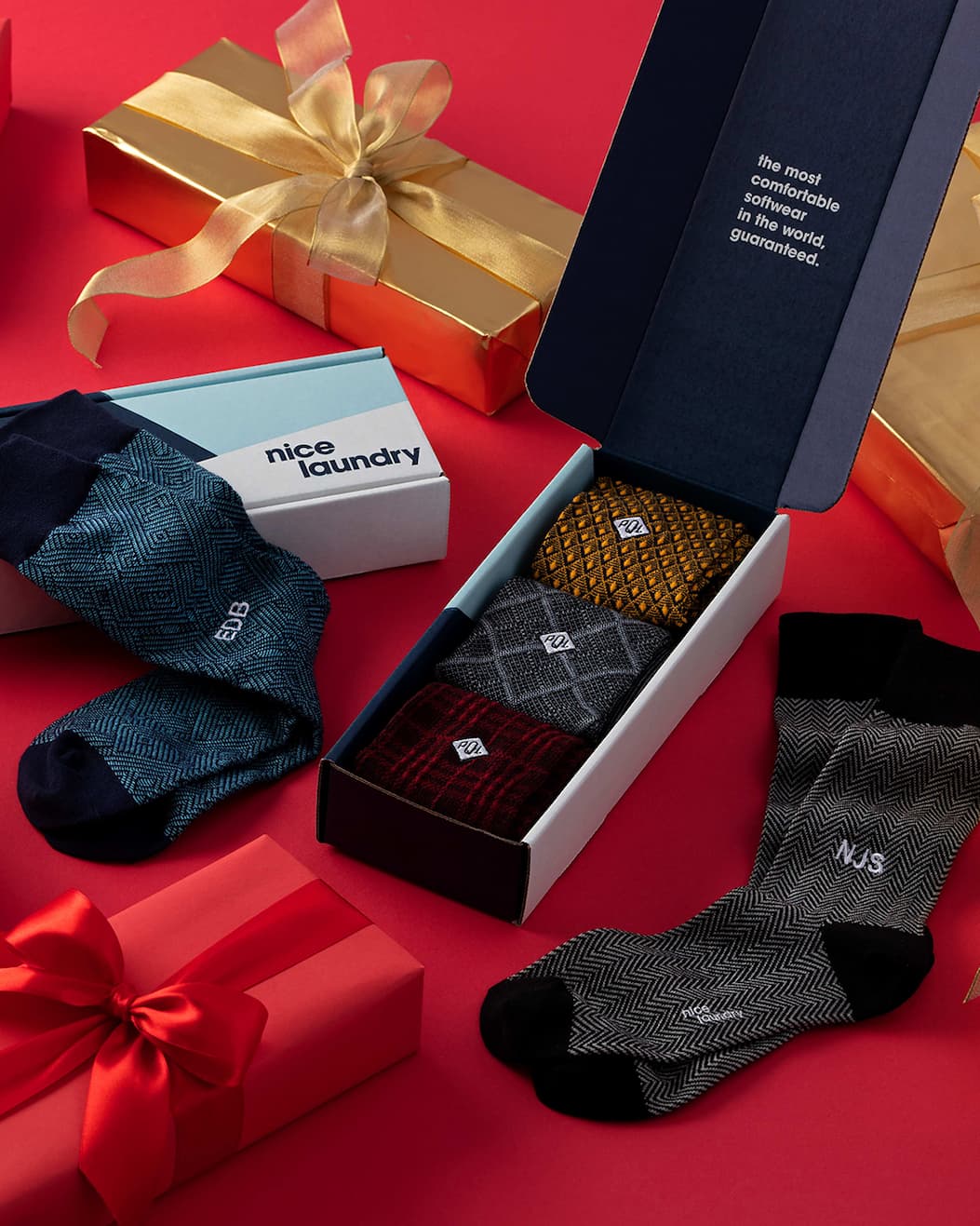 Group of wrapped presents and monogrammed socks on a red background