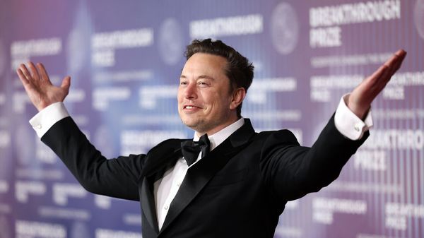 Elon Musk gestures with a smile.