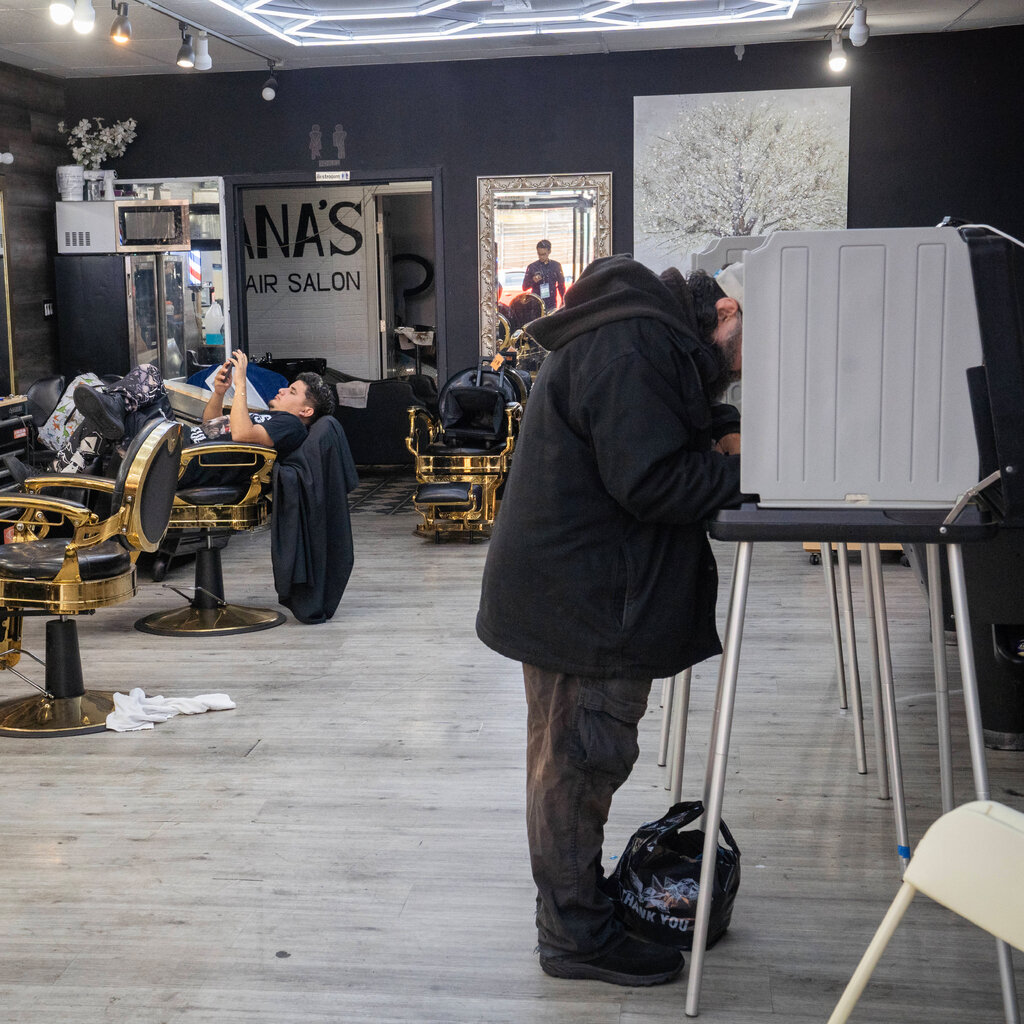 A man votes at a polling place in a barbershop.