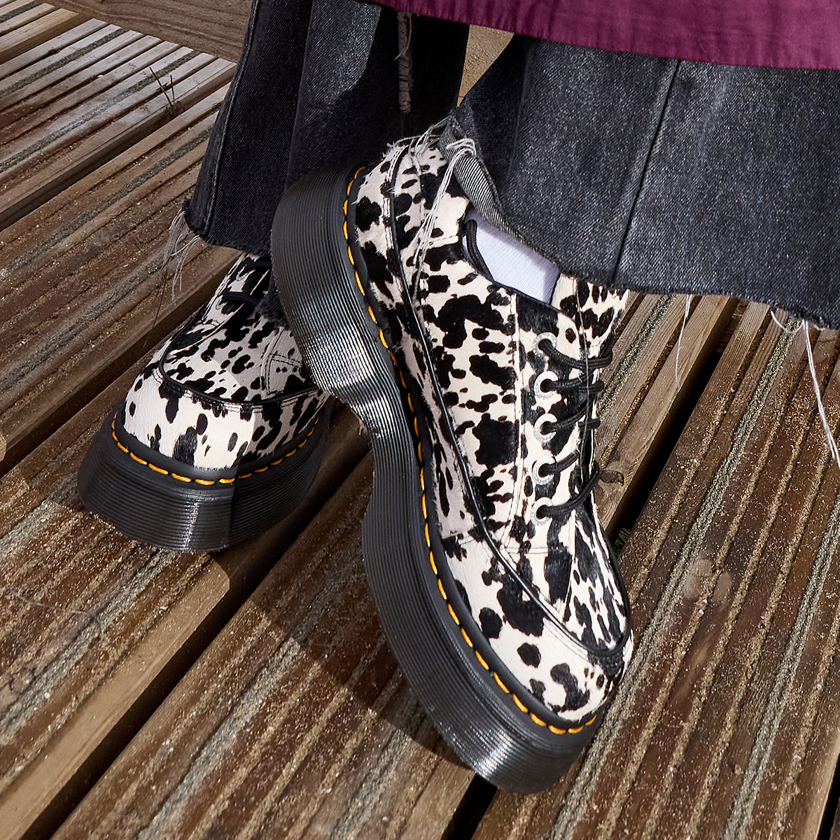 A person's feet wearing cow print Dr. Martens shoes
