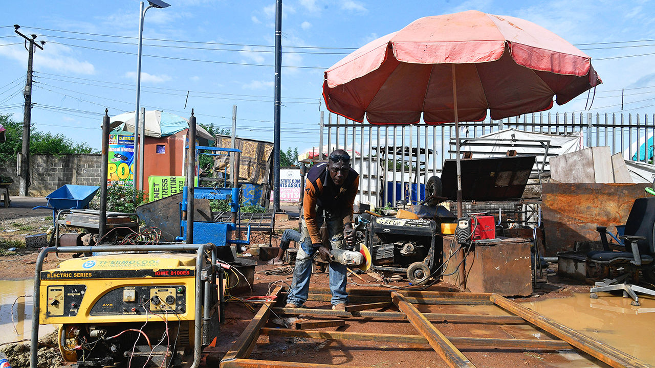 A welder sources power from fuel-powered generator in Nigeria