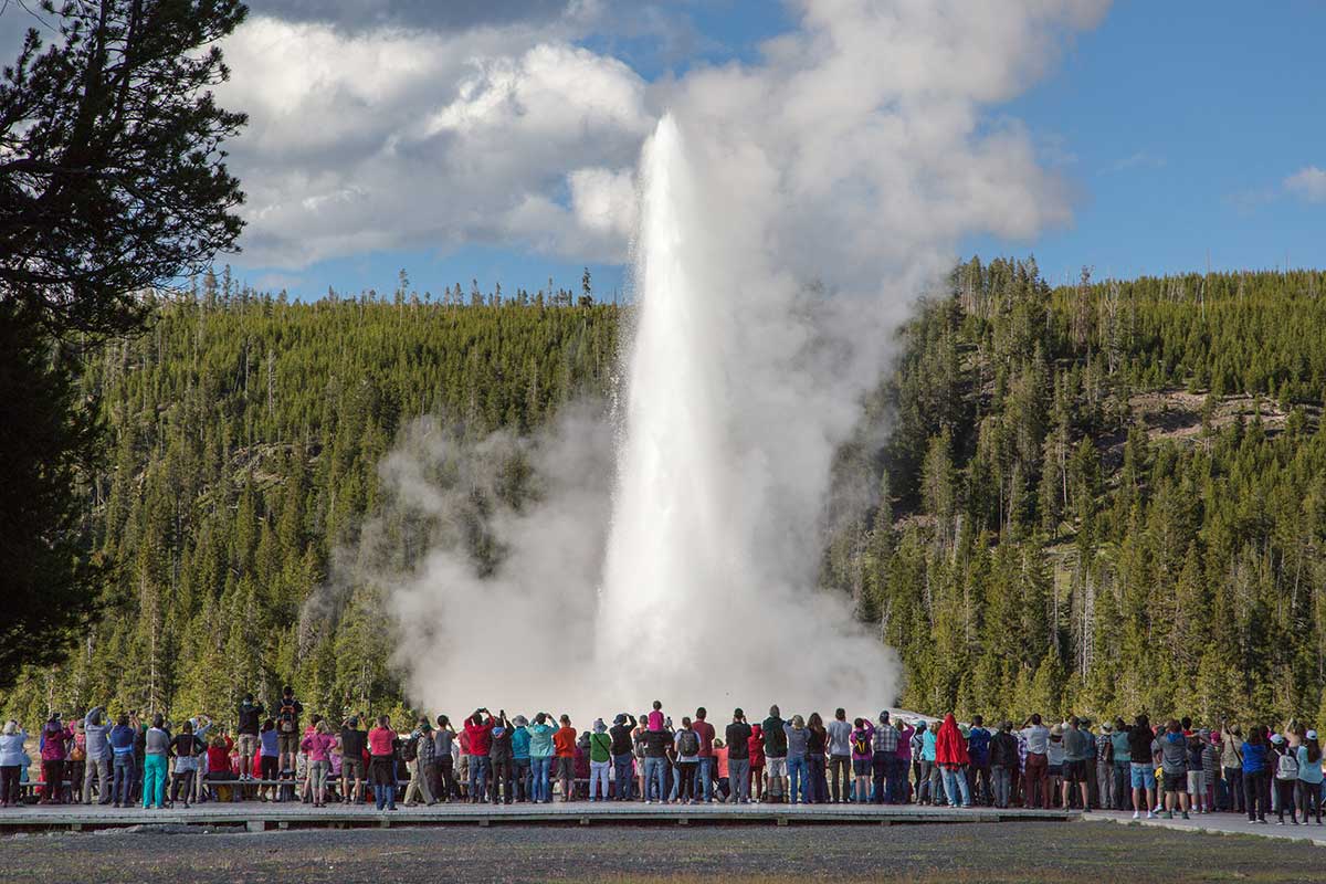 Tourists in front of the erupting Old Faithful geyser