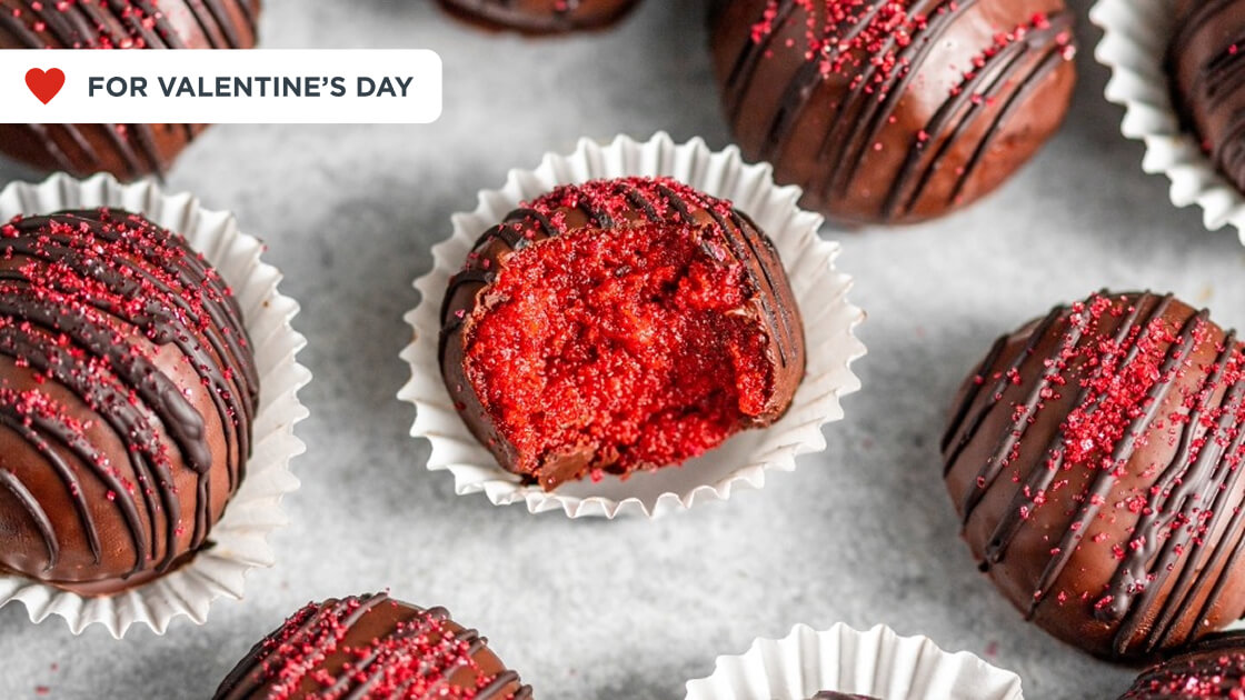  Several red velvet truffles, one with a bite taken out of it in the middle.
