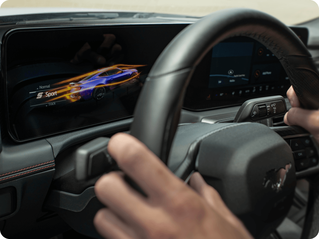 Close‑up of hands on the steering wheel of Ford Mustang&reg; model with dashboard showing Sport mode enabled