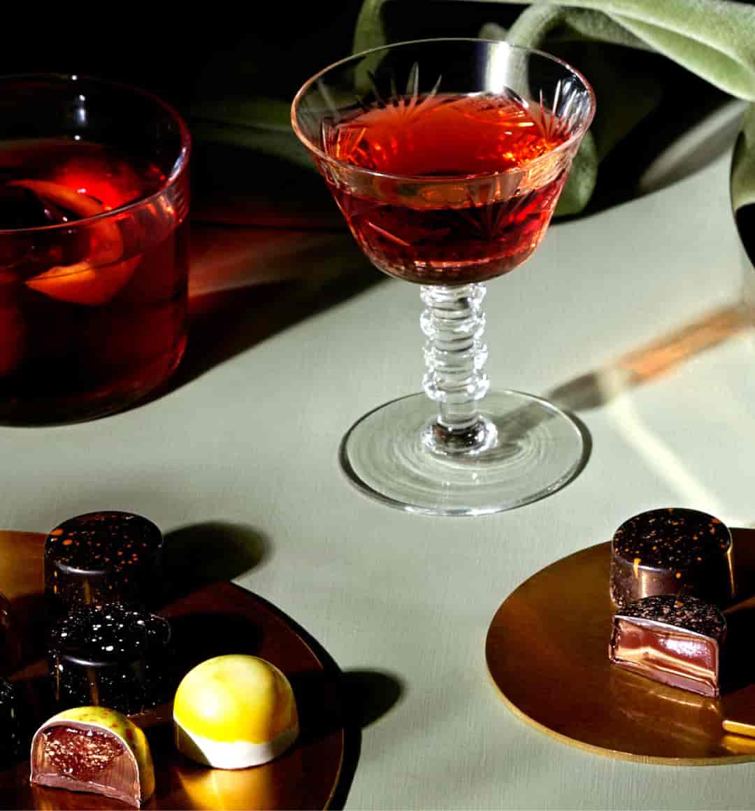 Assorted bonbons from our Aperitivo & Digestivo Collection next to the cocktails that inspired them.