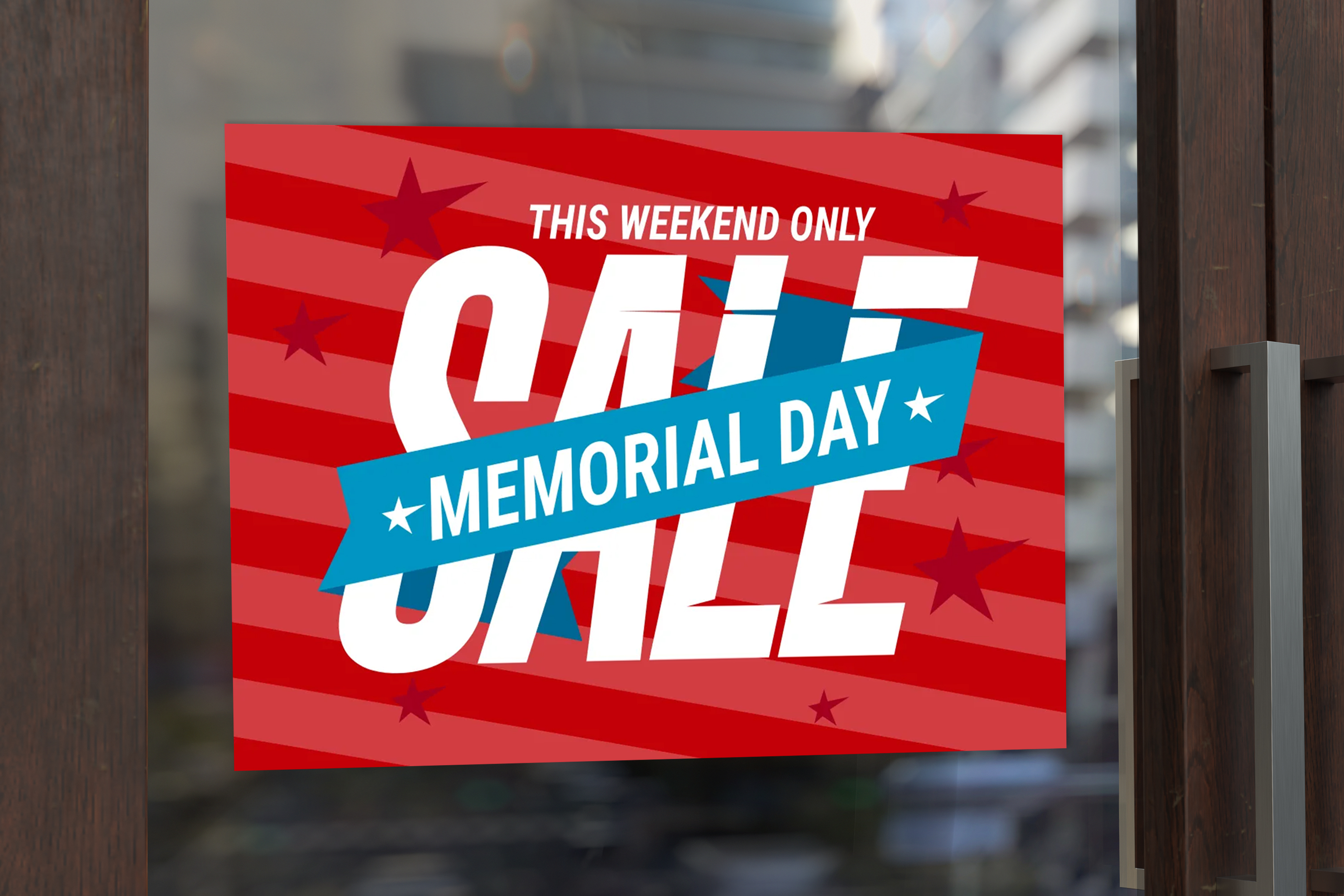 A red Memorial Day sale window decal on a glass door reads “This Weekend Only Sale Memorial Day,” with bold white lettering, diagonal stripes, star graphics, and a blue ribbon banner.