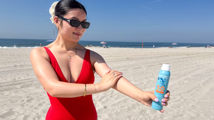 person on beach applying sunscreen