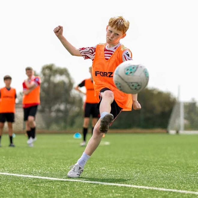 Junior player training with FORZA Academy balls, wearing orange FORZA bibs.