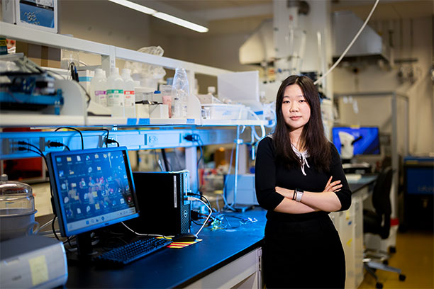 Caitlyn Chen by her desk in the lab.