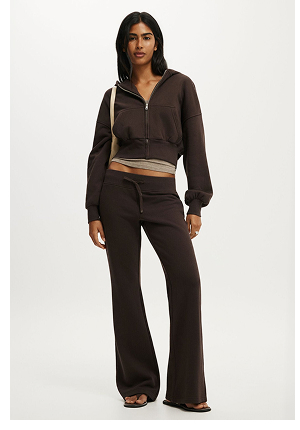 Woman wearing a black cropped zip-up hoodie and black flared pants