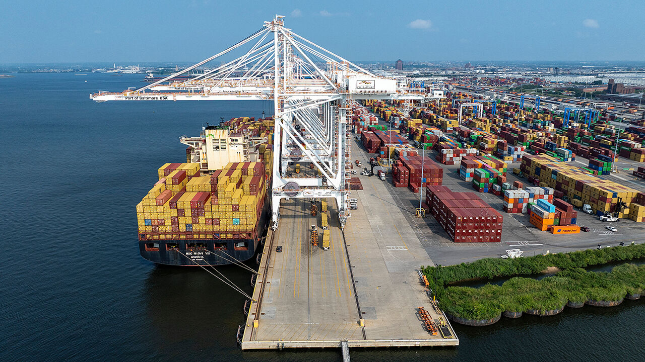 An aerial view of a cargo ship being loaded with shipping containers at Baltimore
