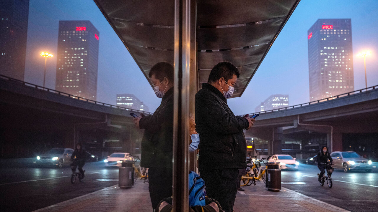 A man looks at his mobile phone while waiting for a bus in China.
