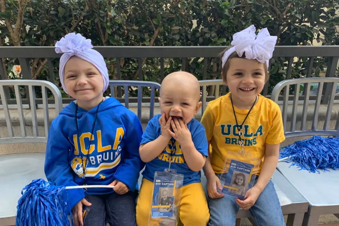 Three young children smiling while wearing UCLA Bruins tops